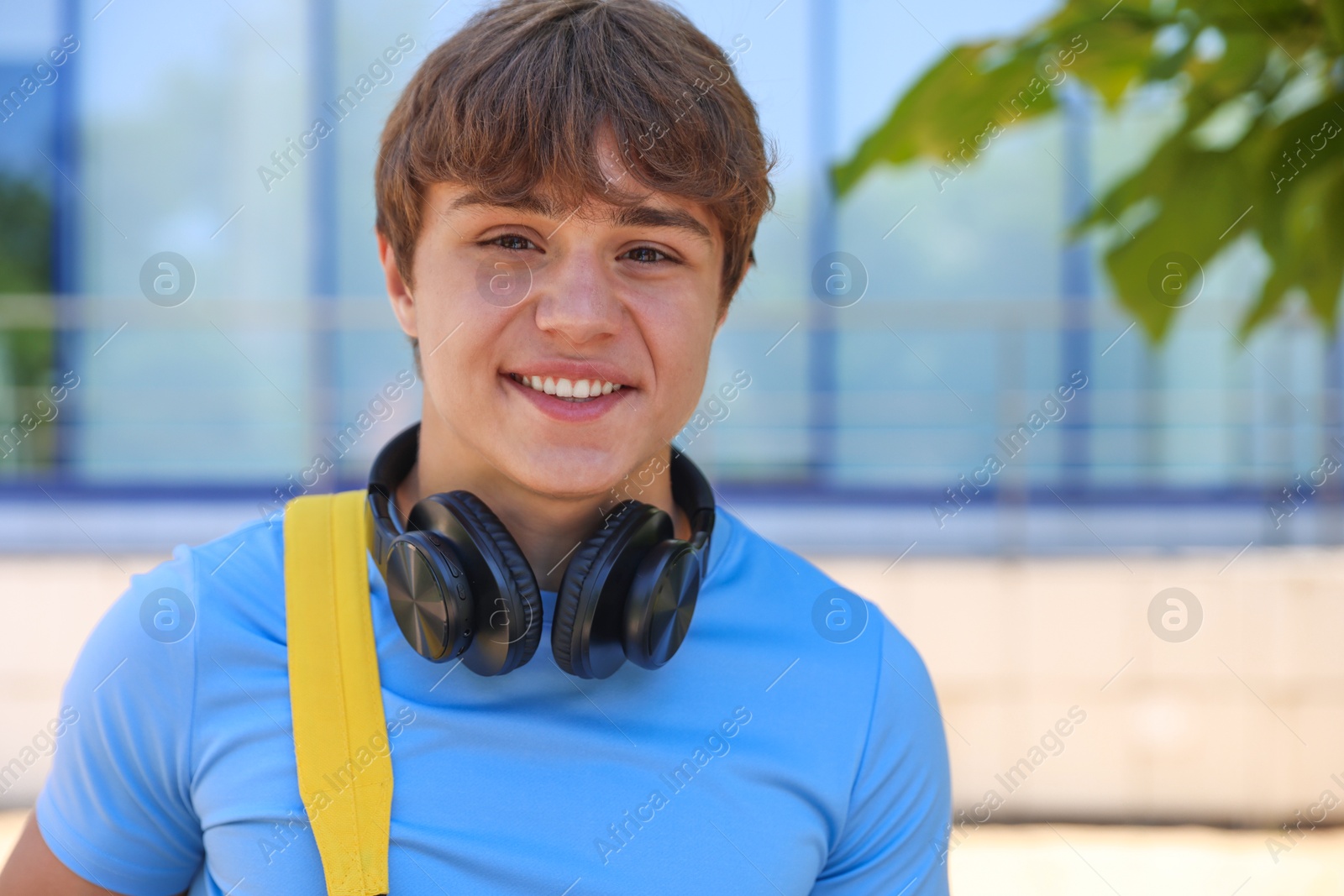 Portrait of smiling teenage boy with headphones on city street Photo of Portrait of smiling teenage boy with headphones on city street