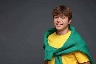 Photo of Portrait of smiling teenage boy on grey background. Space for text