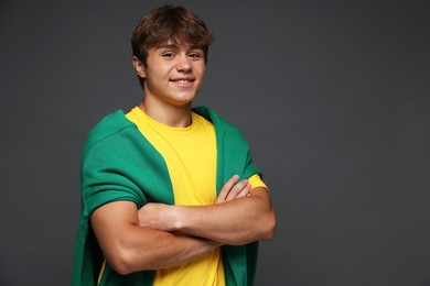 Photo of Portrait of smiling teenage boy with crossed arms on grey background. Space for text