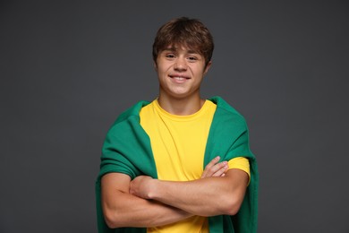 Photo of Portrait of smiling teenage boy with crossed arms on grey background