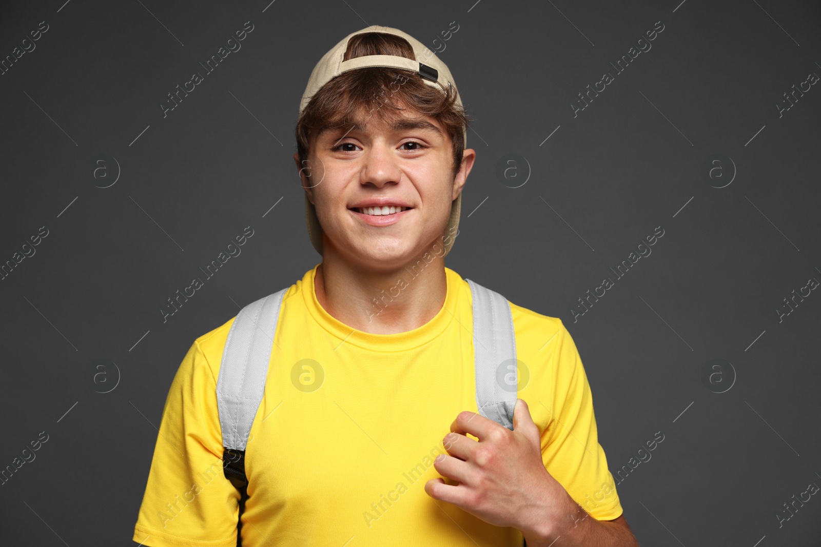 Photo of Portrait of smiling teenage boy in baseball hat on grey background
