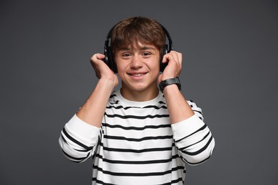 Photo of Portrait of smiling teenage boy in headphones on grey background