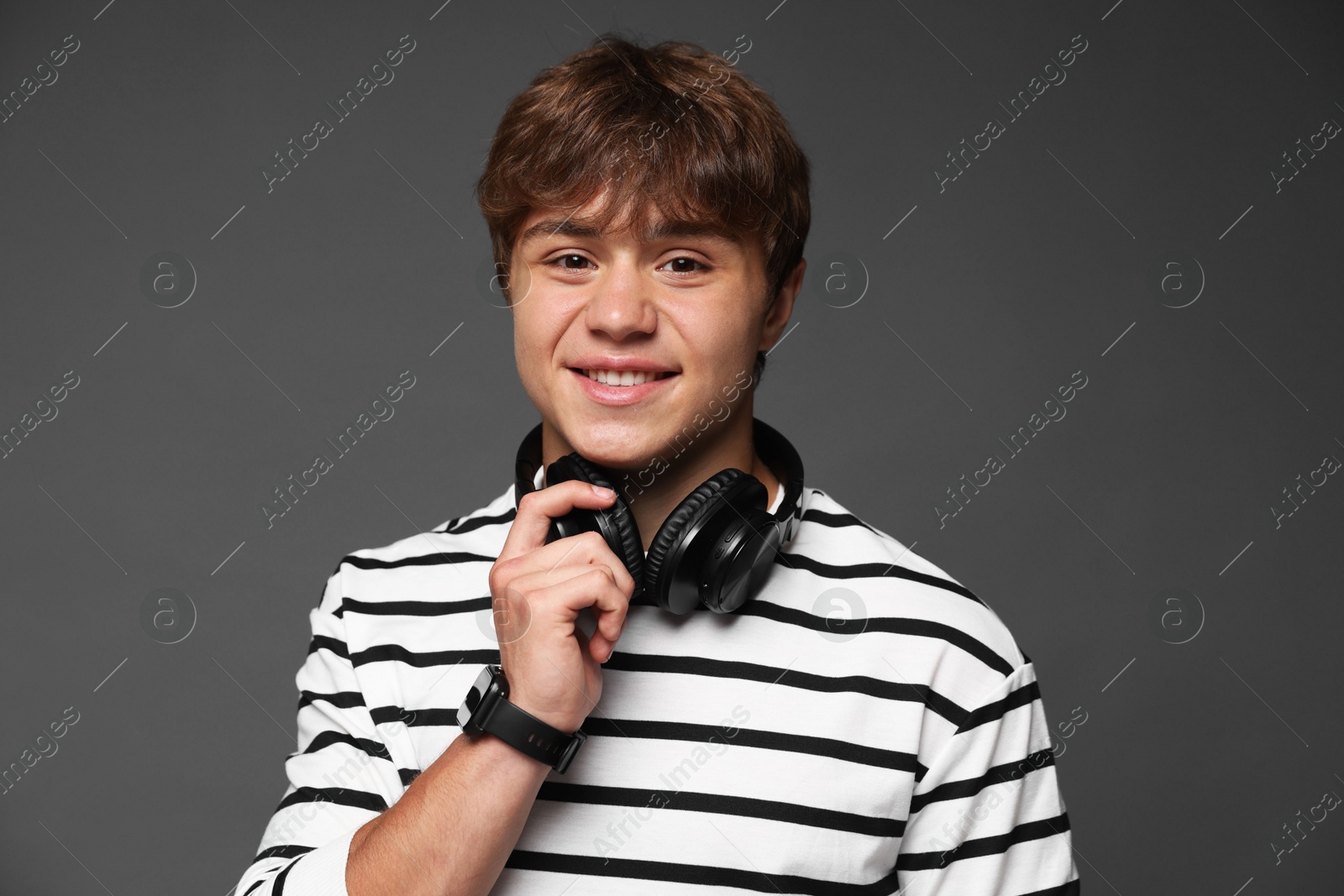 Portrait of smiling teenage boy with headphones on grey background Photo of Portrait of smiling teenage boy with headphones on grey background