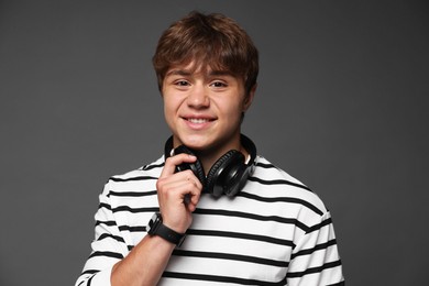 Photo of Portrait of smiling teenage boy with headphones on grey background