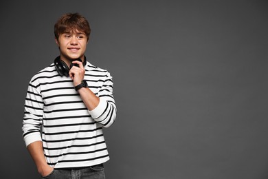 Photo of Smiling teenage boy with headphones on grey background. Space for text