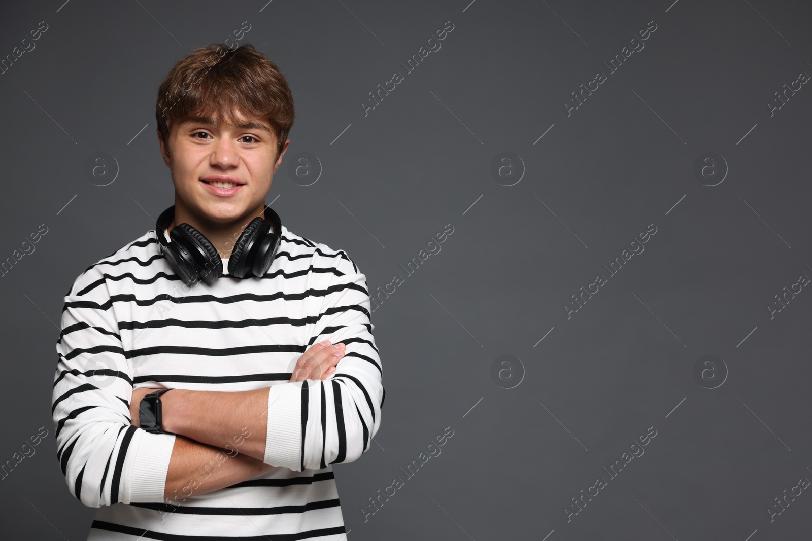 Portrait of smiling teenage boy with headphones on grey background. Space for text Photo of Portrait of smiling teenage boy with headphones on grey background. Space for text