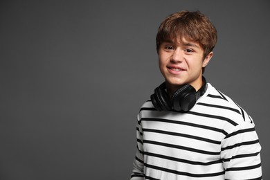 Photo of Portrait of smiling teenage boy with headphones on grey background. Space for text
