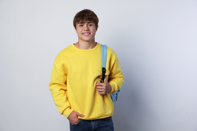 Photo of Portrait of smiling teenage boy with backpack on light grey background
