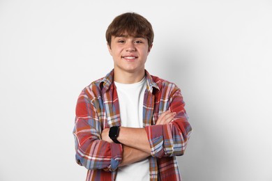 Photo of Portrait of smiling teenage boy with crossed arms on light grey background