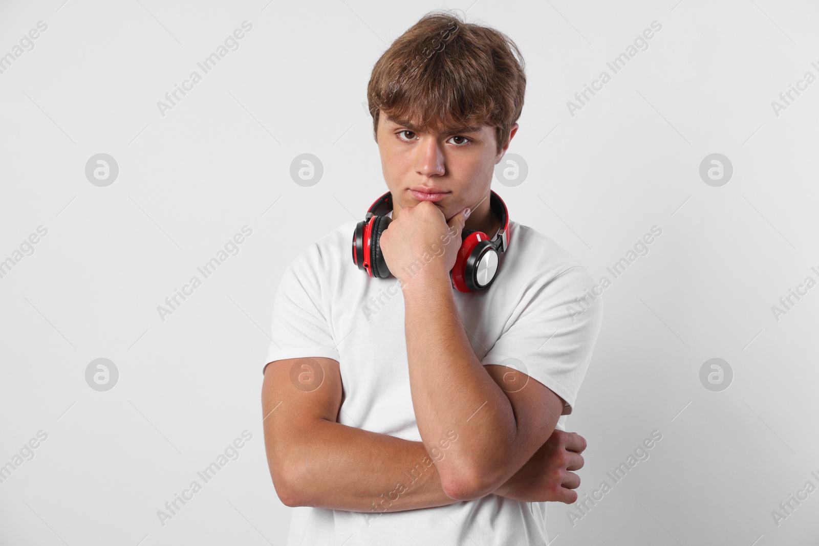 Photo of Portrait of cute teenage boy with headphones on light grey background