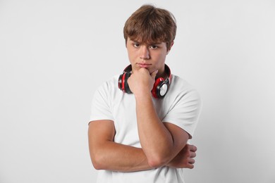 Photo of Portrait of cute teenage boy with headphones on light grey background