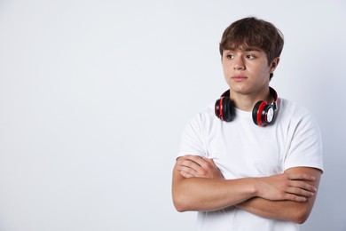 Photo of Cute teenage boy with crossed arms on light grey background. Space for text