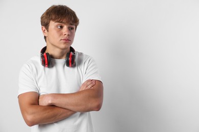 Photo of Cute teenage boy with crossed arms on light grey background. Space for text