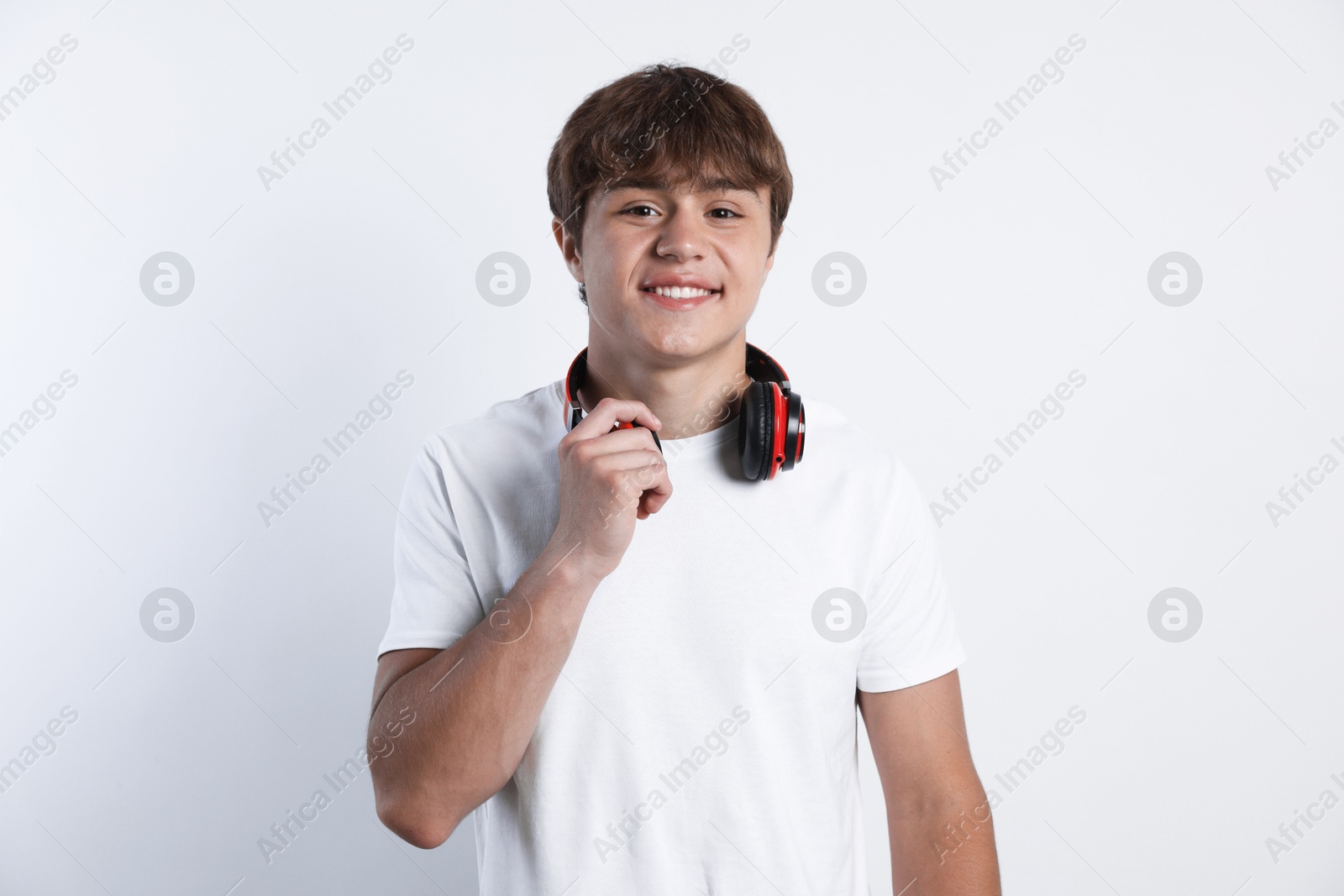 Photo of Portrait of smiling teenage boy with headphones on light grey background