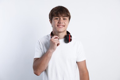 Photo of Portrait of smiling teenage boy with headphones on light grey background