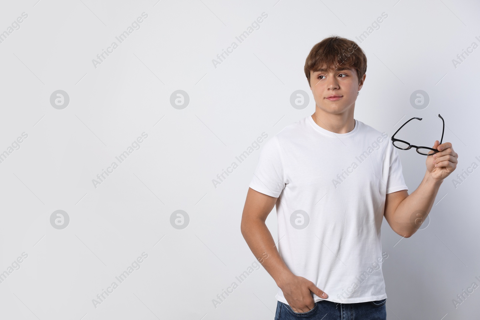 Photo of Cute teenage boy with glasses on light grey background. Space for text