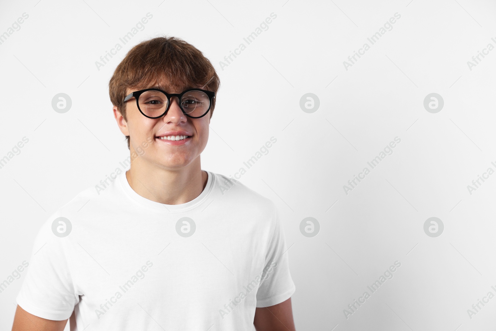 Portrait of smiling teenage boy in glasses on light grey background. Space for text Photo of Portrait of smiling teenage boy in glasses on light grey background. Space for text