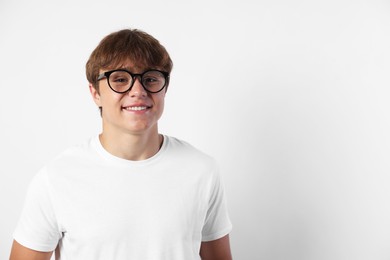 Photo of Portrait of smiling teenage boy in glasses on light grey background. Space for text
