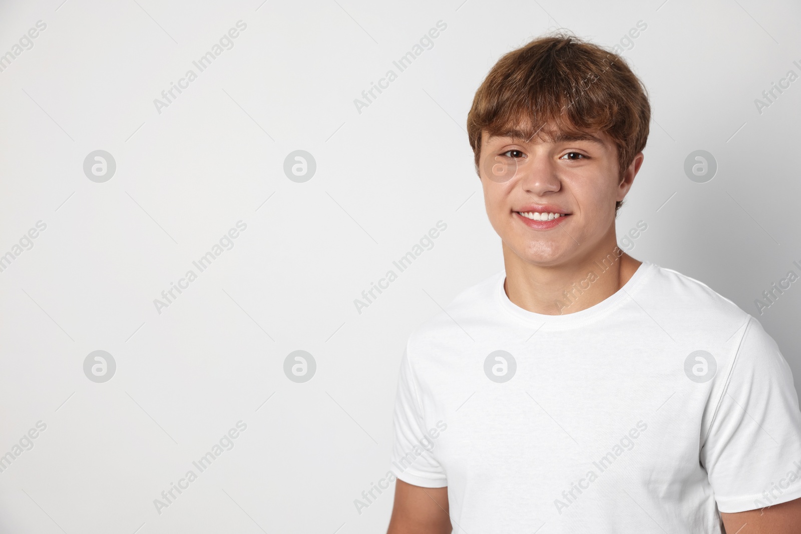 Portrait of smiling teenage boy on light grey background. Space for text Photo of Portrait of smiling teenage boy on light grey background. Space for text