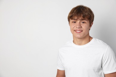 Photo of Portrait of smiling teenage boy on light grey background. Space for text