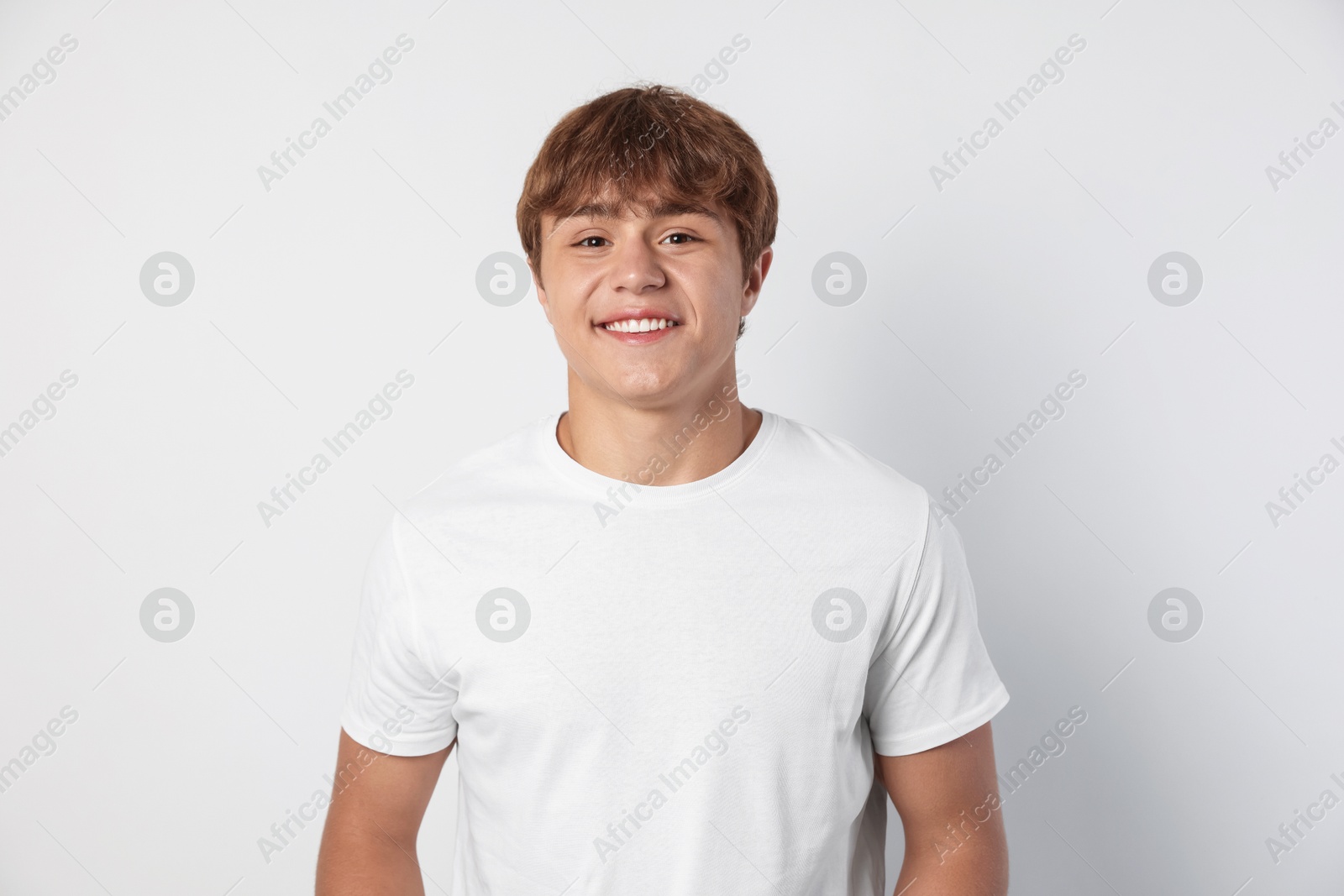 Photo of Portrait of smiling teenage boy on light grey background