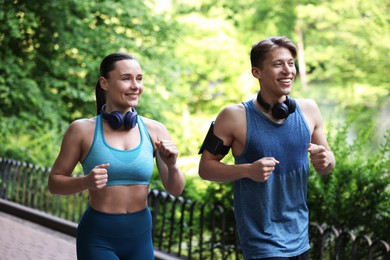Photo of Sporty couple with headphones running in park