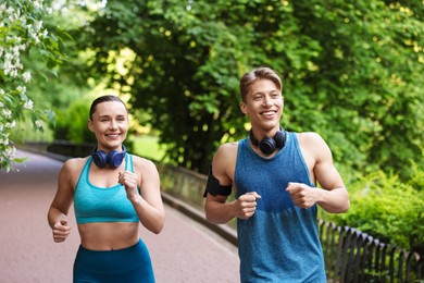 Photo of Sporty couple with headphones running in park