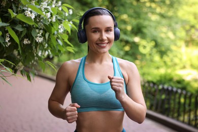 Photo of Sporty woman with headphones running in park
