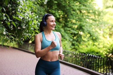 Photo of Sporty woman with headphones running in park