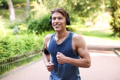 Photo of Sporty man with headphones running in park