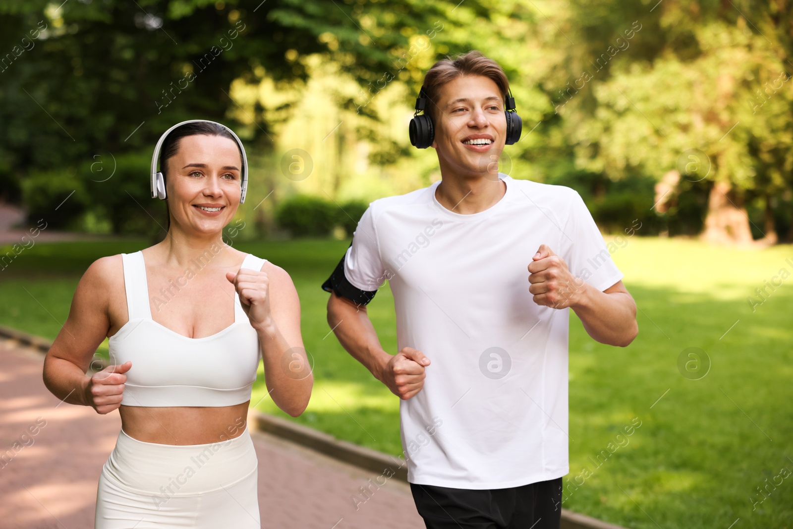 Photo of Sporty couple with headphones running in park