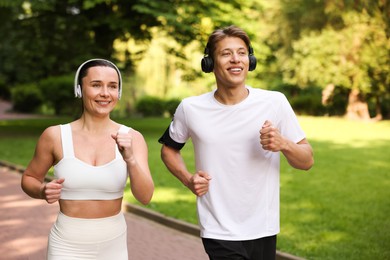Photo of Sporty couple with headphones running in park