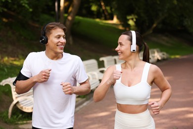 Photo of Sporty couple with headphones running in park