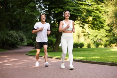 Photo of Sporty couple with headphones running in park
