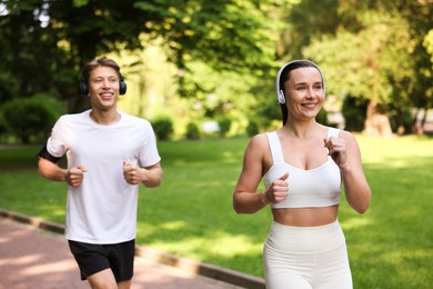 Photo of Sporty couple with headphones running in park