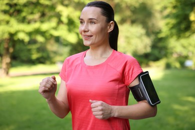 Photo of Sporty woman with armband running in park
