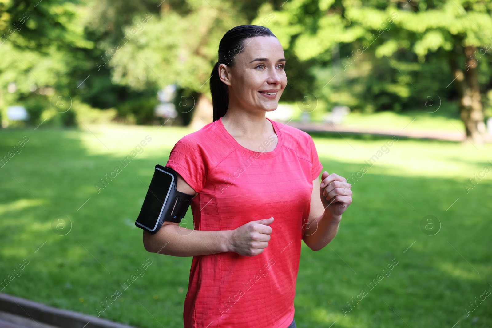 Photo of Sporty woman with armband running in park