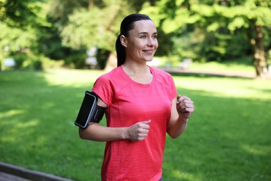 Photo of Sporty woman with armband running in park
