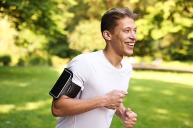 Photo of Sporty man with armband running in park