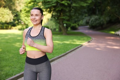 Photo of Sporty woman running in park, space for text