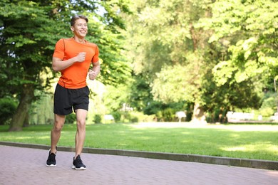 Photo of Sporty man running in park, space for text