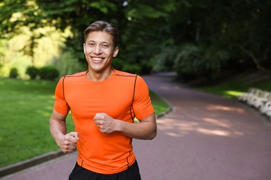 Photo of Sporty man running in park, space for text