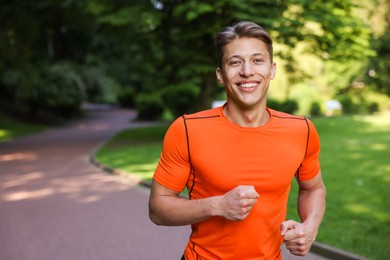 Photo of Sporty man running in park, space for text