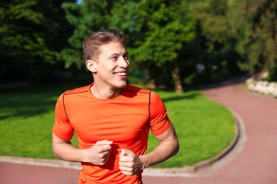 Photo of Sporty man running in park, space for text