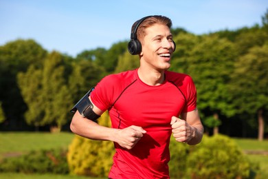 Photo of Sporty man with headphones running in park