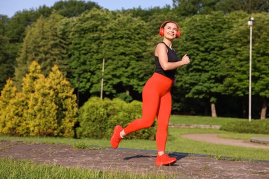 Photo of Sporty woman with headphones running in park