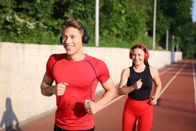 Photo of Sporty couple running at stadium, selective focus