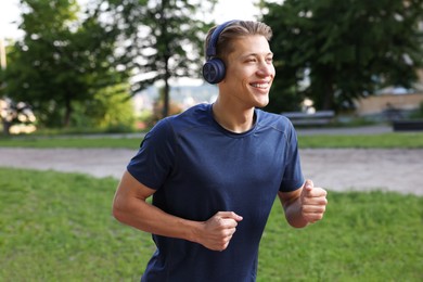 Photo of Sporty man with headphones running in park