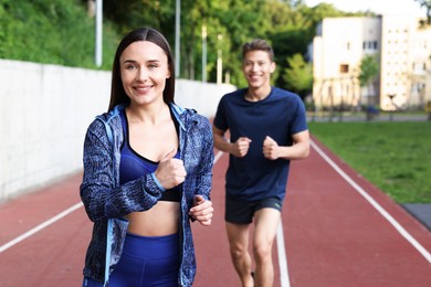 Photo of Sporty couple running at stadium, selective focus