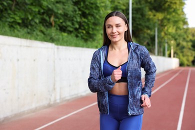 Photo of Sporty woman running at stadium, space for text